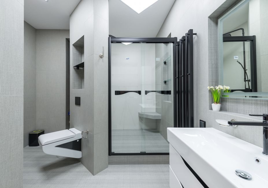 Sink with tap placed at wall with mirror in light spacious bathroom with toilet and glass shower cabin in apartment